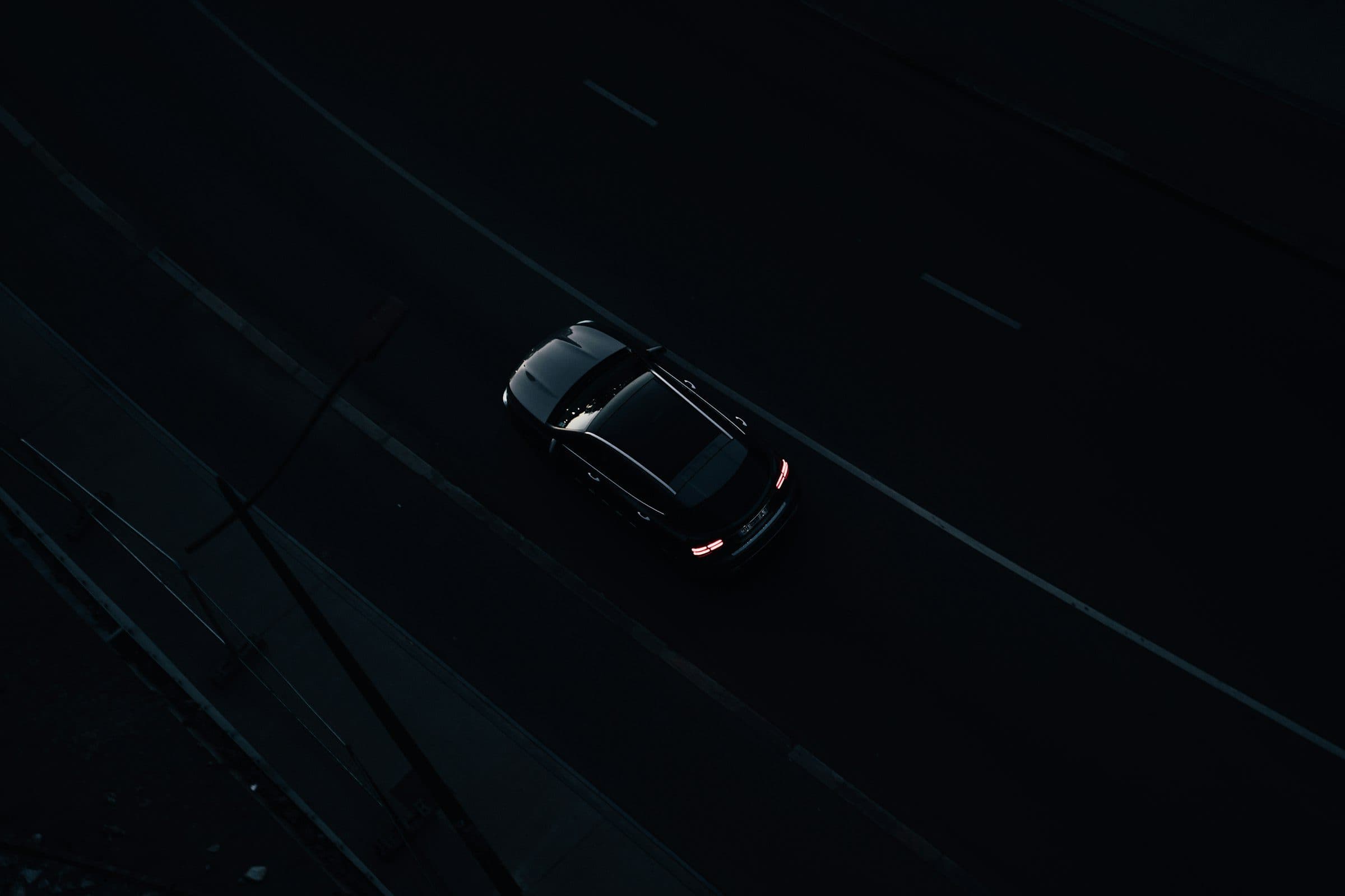 Un’auto scura vista dall’alto su una strada di notte